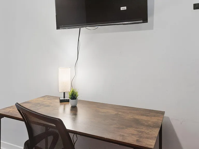 Dedicated work nook with a sturdy desk, task lighting, and wall-mounted TVideal for studying, remote work, or streaming.