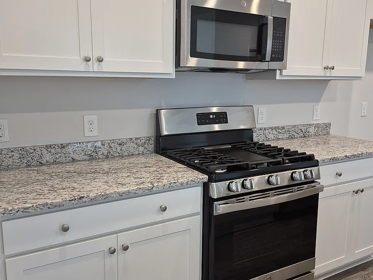 Beautiful white kitchen cabinetry, gas stove and microwave