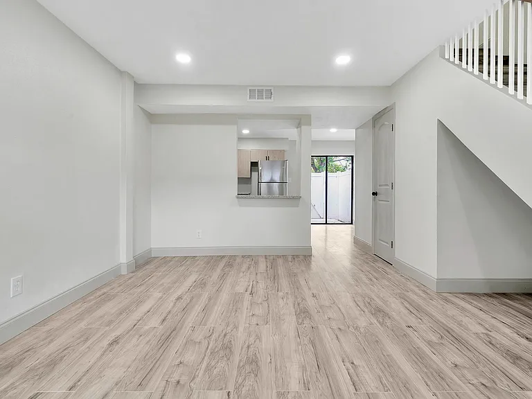 Bright and spacious open-concept living area with modern wood flooring and large sliding glass doors leading to a private patio.