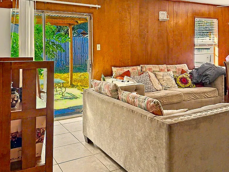 Living room with tile flooring, ceiling fan, and a comfortable seating area with sliding doors to the backyard patio.