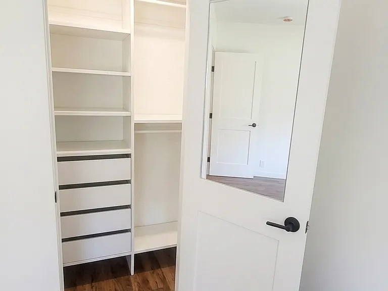 Back bedroom with a custom-built-in closet and custom mirror inside the closet door