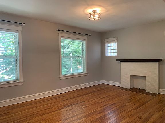 living room is large and gracious with decorative fireplace and other architectural details; faux wood blinds are provided in every room but note attractive iron curtain rods which would allow for hanging drapes if desired