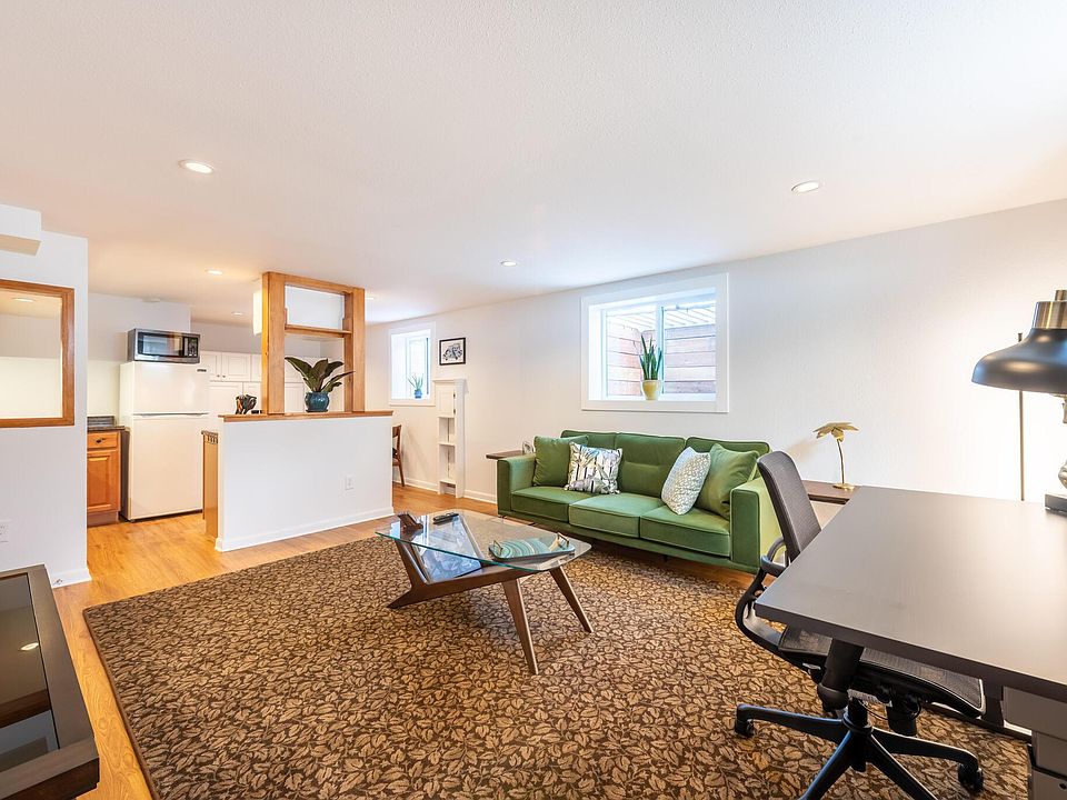 Living room and workspace area complete with standing desk and ergonomic chair.