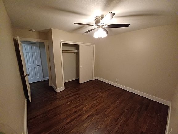 Hardwood bedroom with ceiling fan and full closet.