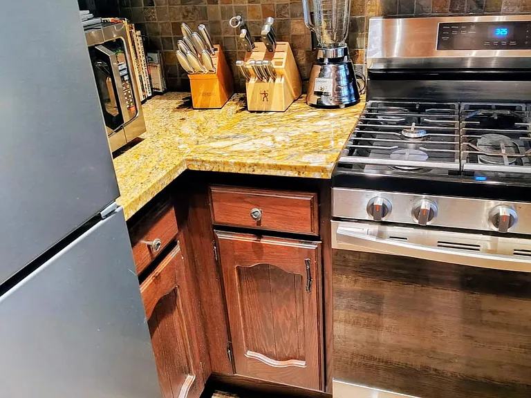 Kitchen corner with granite counters, tile backsplash, ample wood cabinetry, and stainless steel gas range for everyday cooki