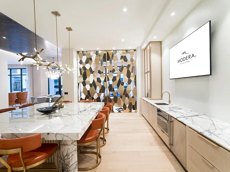 A stylish catering kitchen at Modera Liberty Row offers ample prep space, marble surfaces, and seating designed for hosting and everyday convenience.