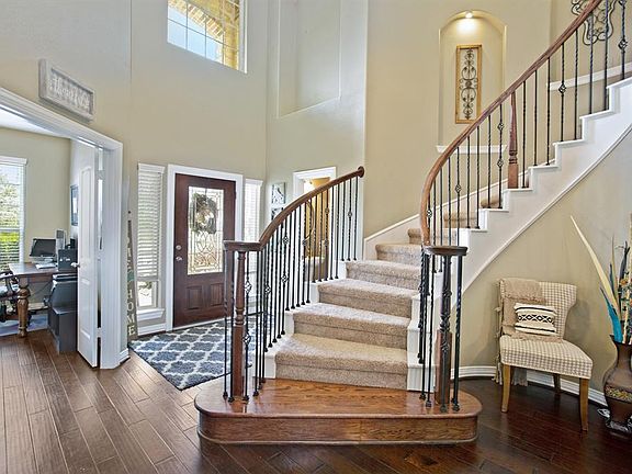 Elegant staircase with wrought iron spindles, lighted art niches, 2 story ceiling and hardwoods.