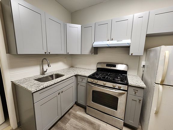 Stainless Steel Range + White Refrigerator. Grey cabinets.