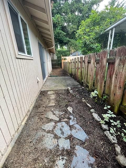 picture from fence/flower garden area towards back of rest of yard (L shaped) , window to the left is to the kitchen, then patio & on left sliding door
