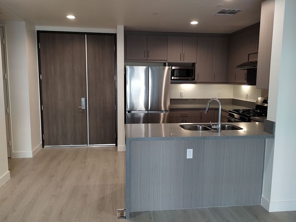 kitchen with brand new fridge, microwave & stove, double door entry, quartz counter and laminated wood flooring