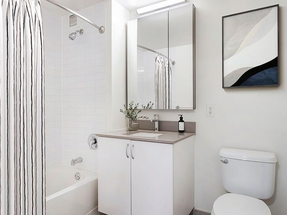 Updated Finishes bath with white cabinetry, grey quartz countertops, and hard surface flooring