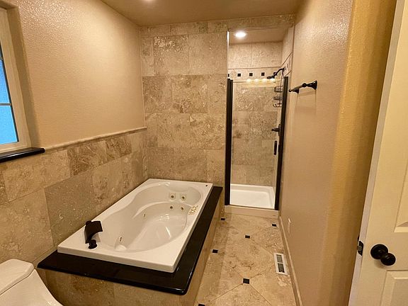 Travertine spa master bath with dual shower heads, jacuzzi spa and dual vanities.