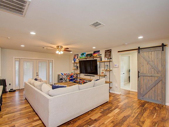 The living room features several shelving areas, including this custom-built wall unit. From the living room, you can also access the backyard from the French doors and also the hallway to the bedrooms and bathrooms.