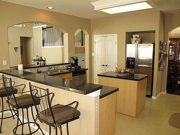 This beautiful kitchen nestled behind arched entries has it all; granite island, stainless steel appliances, 42" cabinetry, tile floor & backsplash, and a large breakfast bar!