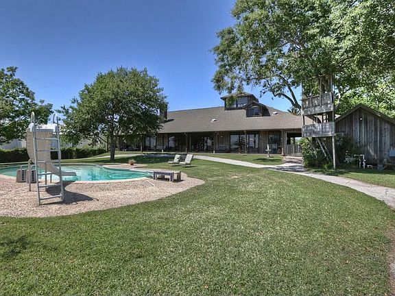 A deep covered veranda extends across the back of the house with sweeping views of the lake and the rolling lawn. Accessible from the Living Room, Master Bedroom and Kitchen. A paved drive from the porte-cochere leads to the private boat ramp.