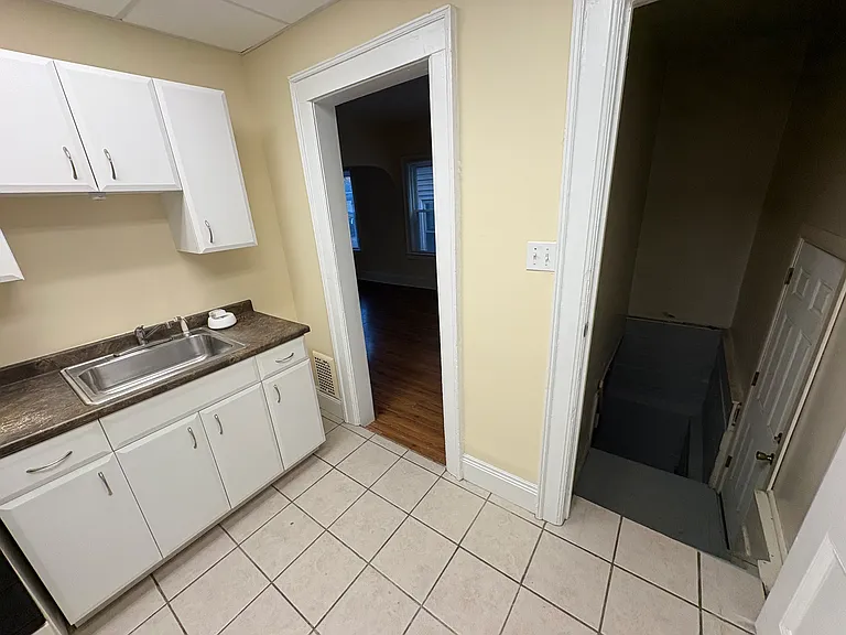 Entrance to kitchen from the living room (left). To the right is a stairwell (with an open door which locks) leading to the basement. The stairwell also has a brand new door (with bolt lock) which leads to the rear of the building.