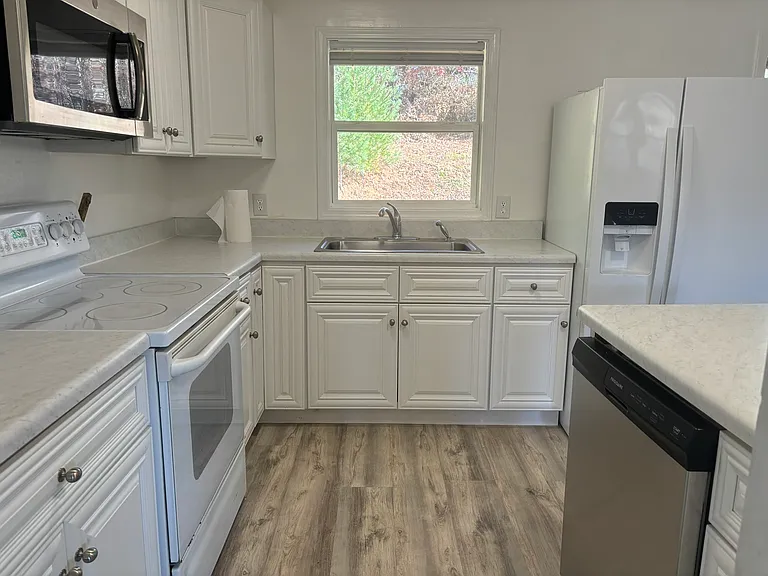 Bright kitchen with new dishwasher and also has a refrigerator, built-in microwave and range/oven.