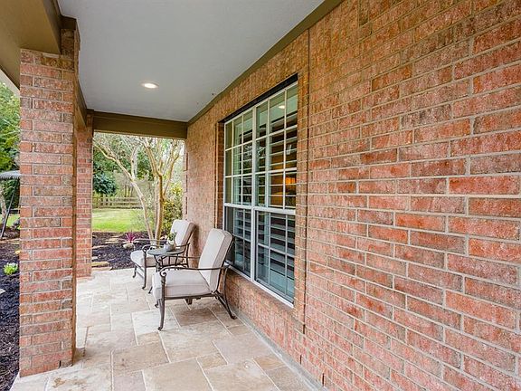 Another view of the spacious porch that provides plenty of room for seating for relaxing and enjoying views of the front gardens, lawn and beautiful natural greenspace that surrounds much of this property.