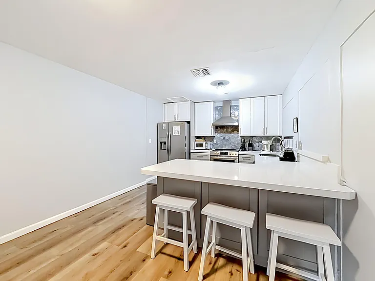 Eat-in kitchen with a large breakfast bar, ample white cabinetry, and stainless steel appliances for everyday cooking.