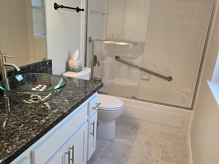 Thoughtfully renovated second en-suite combines elegant granite countertops, designer fixtures, and a full glass-enclosed tub/shower.