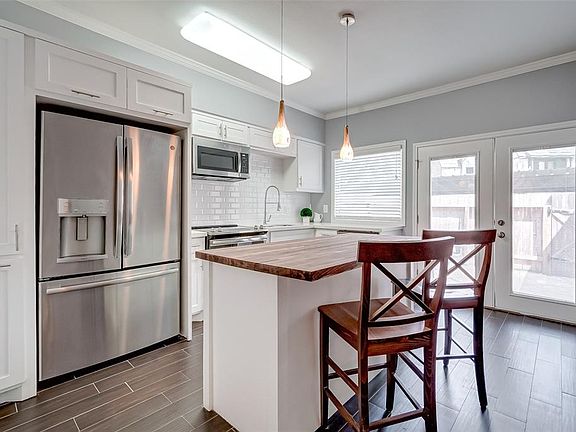 A recently remodeled first floor, including the kitchen, with newer appliances, white subway tile and white cabinets. The gorgeous butcher block has room for counter-height bar stools. The kitchen looks out through french doors onto the back patio. (
