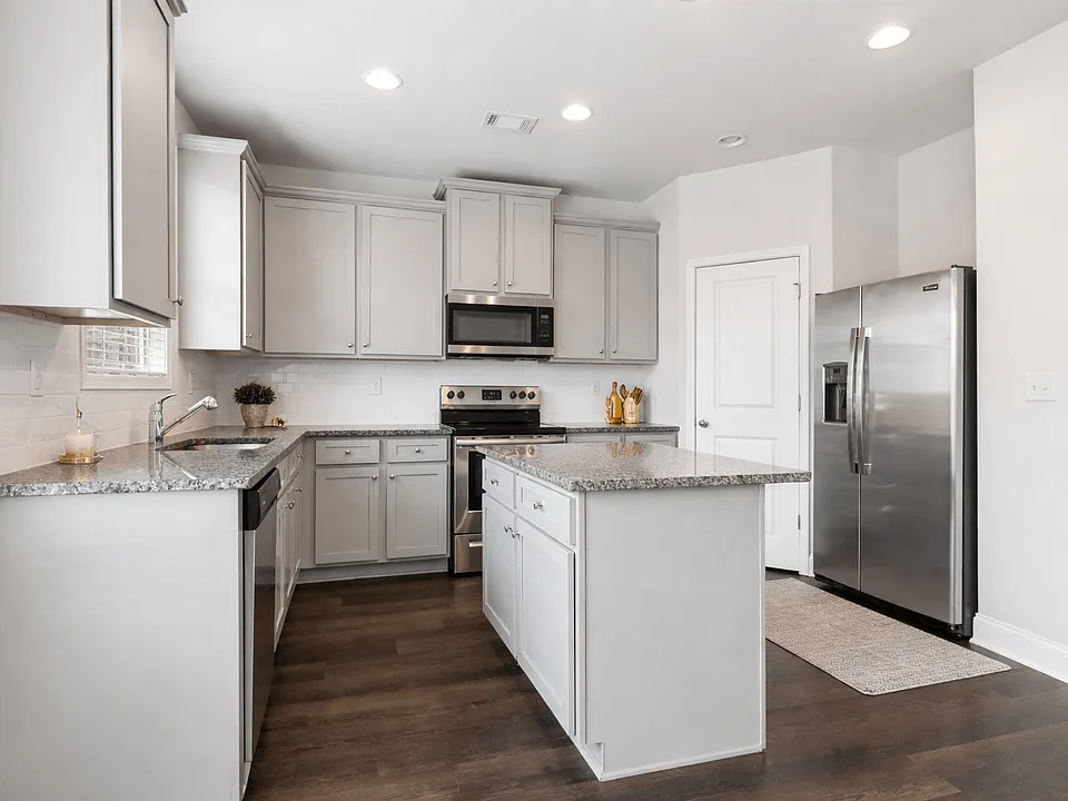 Spacious kitchen with an island, ample storage, stainless steel appliances and view into the living room.