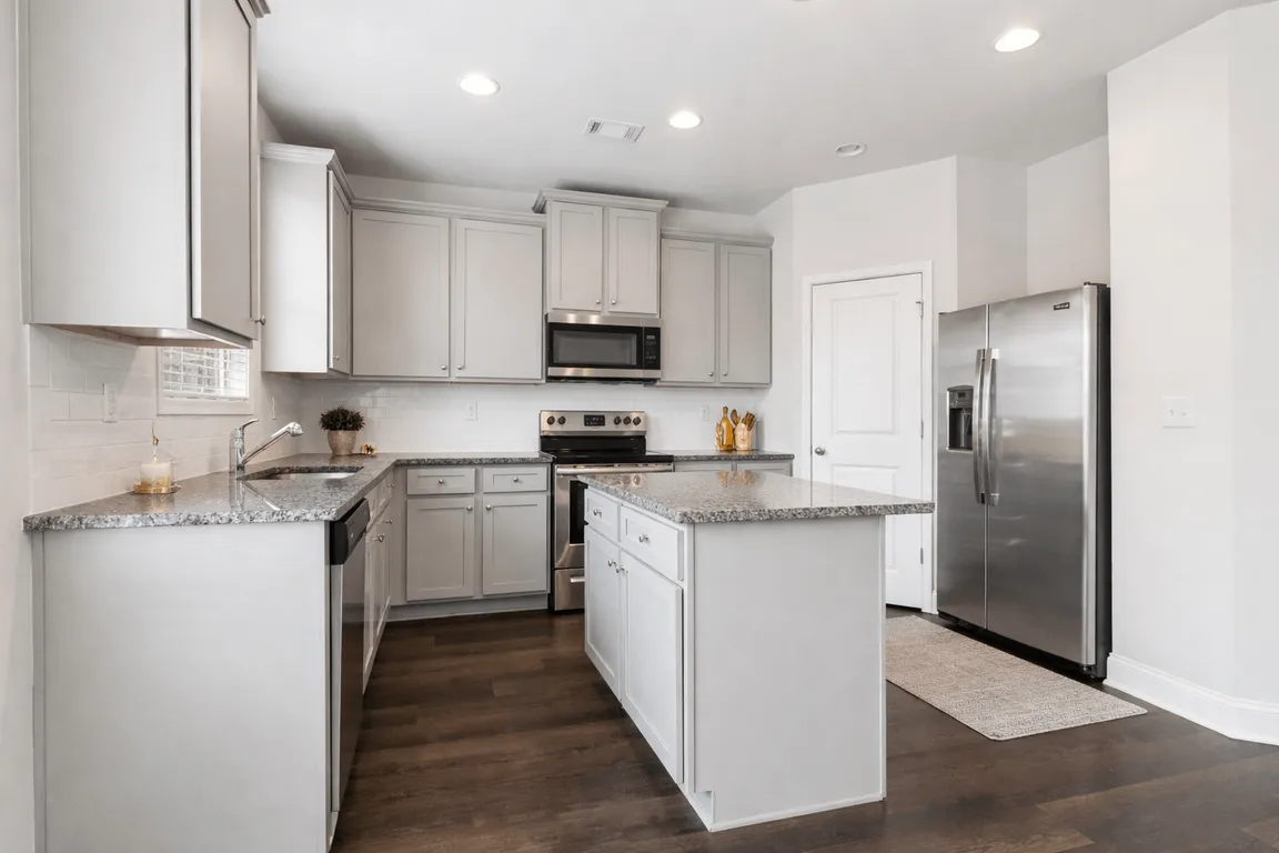 Spacious kitchen with an island, ample storage, stainless steel appliances and view into the living room.