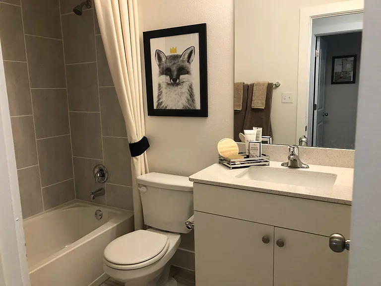 Full bathroom with tiled tub/shower combo, vanity with countertop and sink, and convenient towel storage.