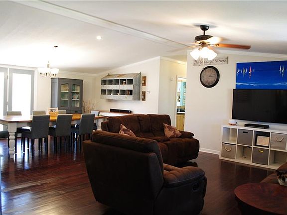 Open floor plan living room and dining room featuring dark stained tongue and groove hardwood floors. Just off the French doors in the dining room is a large back deck.