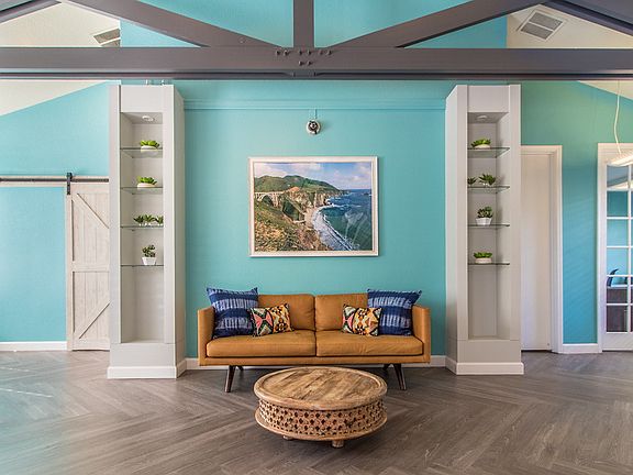 Lobby of leasing office with hardwood style flooring, sofa, and high ceilings.