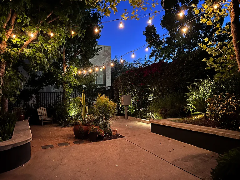 Beautifully landscaped communal garden featuring secure gated entry and curated, artistic night lighting.