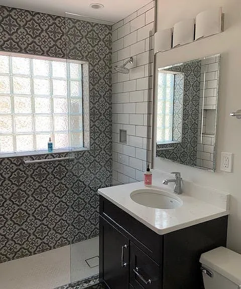 Vintage-style Moroccan tile on the shower wall and floor with modern subway tiles combines for a very unique look you will love. Vanity top is quartz with a stylish one-handle chrome faucet. The large medicine cabinet has mirrors on both sides and lots of