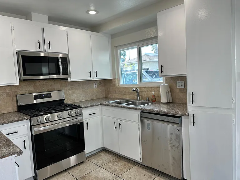 Kitchen showing dishwasher, microwave, range and window to the front parking in front of garage