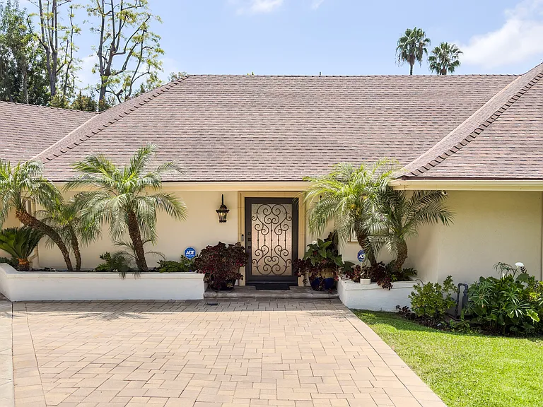 Palm-lined entrance and a dramatic wrought iron door boost curb appeal at this Beverly Hills luxury rental, 1094 Garden Lane, a premier 90210 lease.