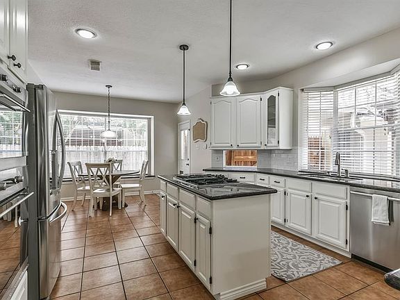 The open concept kitchen has stainless appliances with granite counter tops and white cabinets.