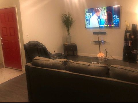 Front door and Living room (including 65 in. Smart TV, couch, recliner, and tables)