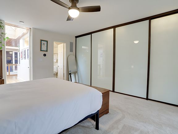 The spacious primary bedroom is in the back of the house and overlooks the patio and cherry tree. Features a queen-sized bed, dresser, privacy and blackout curtains, large closet, and ensuite bathroom.