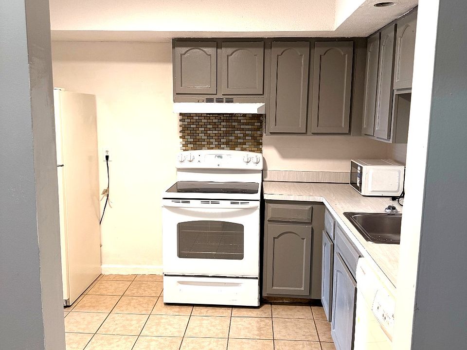 Updated kitchen with gray cabinets, tile flooring, and included appliances