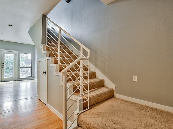 Carpeted staircase featuring a decorative metal railing