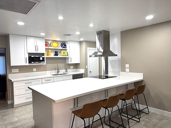 The focal point of the kitchen is the island which is home to an electric Samsung cooktop and stainless oven vent.