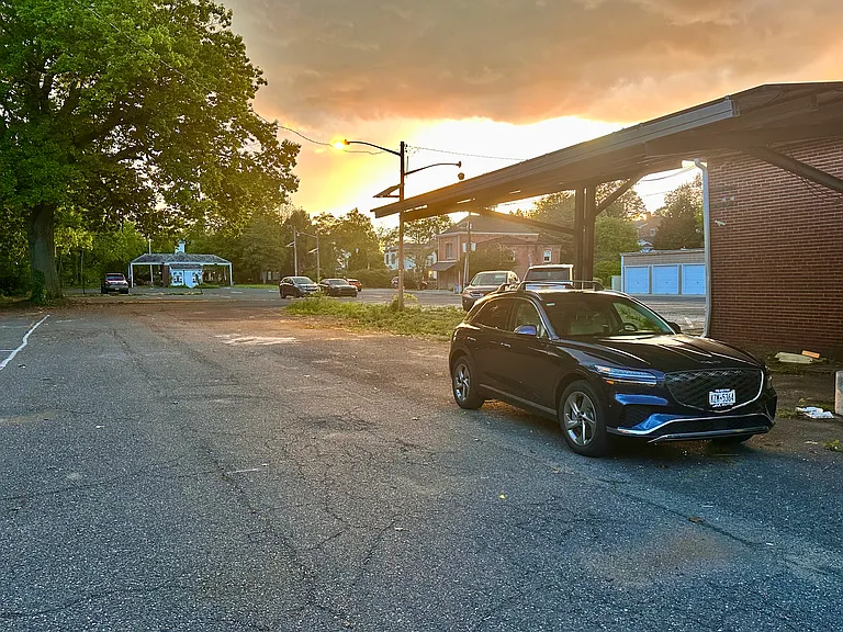 Well-lit private parking lot by rear staircase entrance.