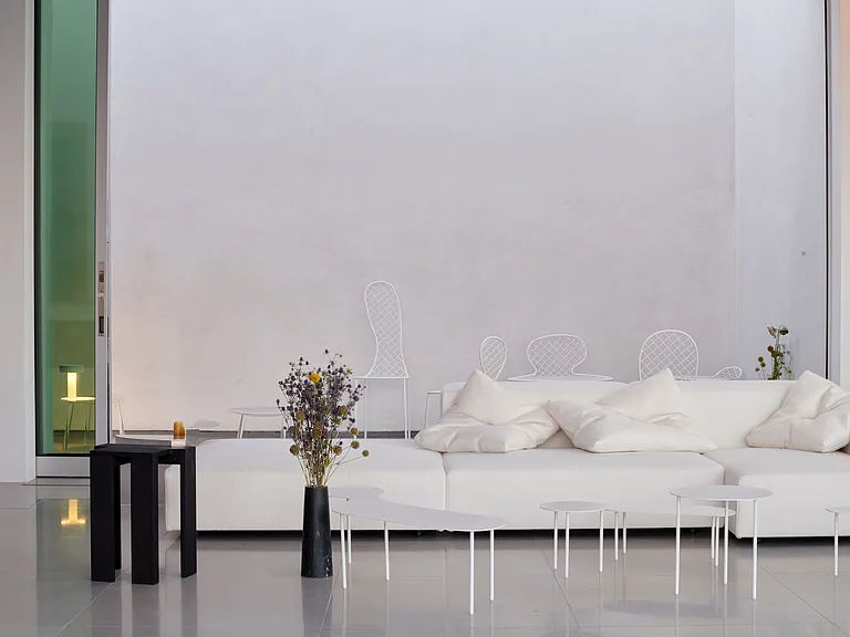 Minimalist Lounge with Seamless Indoor-Outdoor Flow _ A serene and airy living space featuring and floor-to-ceiling glass doors that open to a private outdoor retreat.