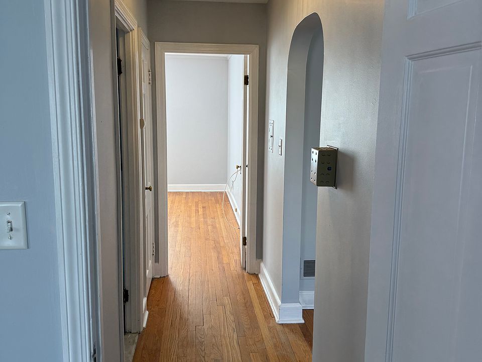 View of corridor from 1 bedroom to the other, with the bathroom being on the left and the archway leading into the dining room