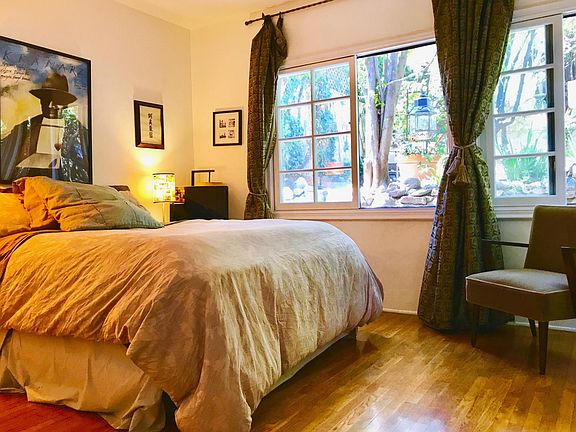 Bedroom has large windows that look out onto the private gar