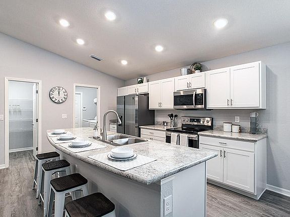 Open kitchen with white shaker-style cabinets, a counter-height Island, and Samsung SS appliances -