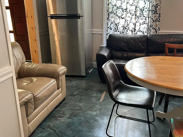Shared lounge and dining nook with seating, a round table, and a window with curtains for everyday meals and relaxing.