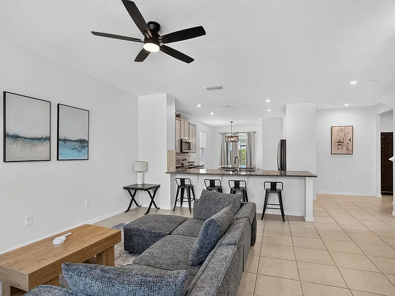 Open-concept living area with tile floors, ceiling fan, and a large breakfast bar overlooking the kitchen for easy dining.