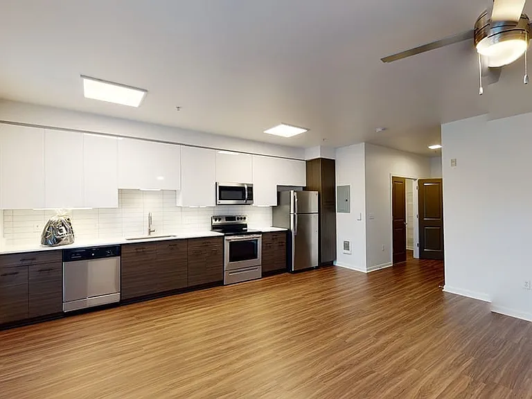 Gourmet kitchen with stainless steel appliances, dining and living room with wood-style flooring.