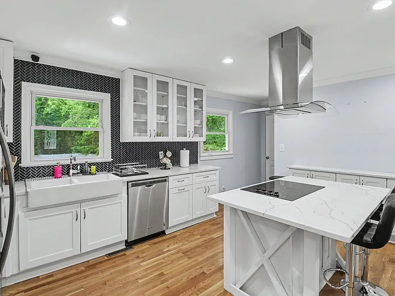 Kitchen 1: updated with white cabinetry, quartz counters, island cooktop seating, and stainless appliances