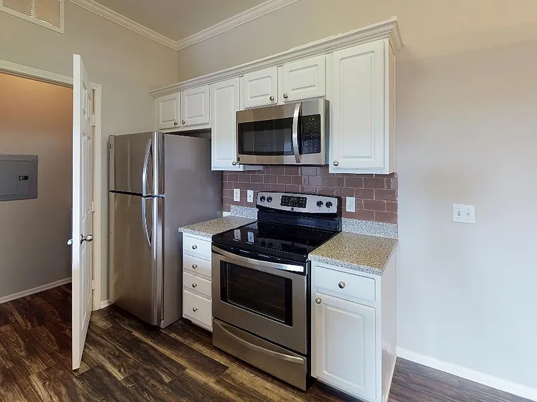 Apartment kitchen with stainless steel appliances in select homes and wood-style flooring.